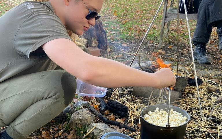 student cooking outdoors